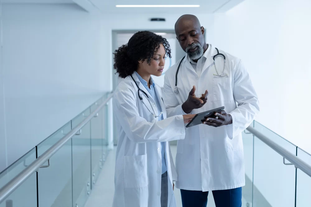 Two doctors looking at a tablet in the hallway of the hospital
