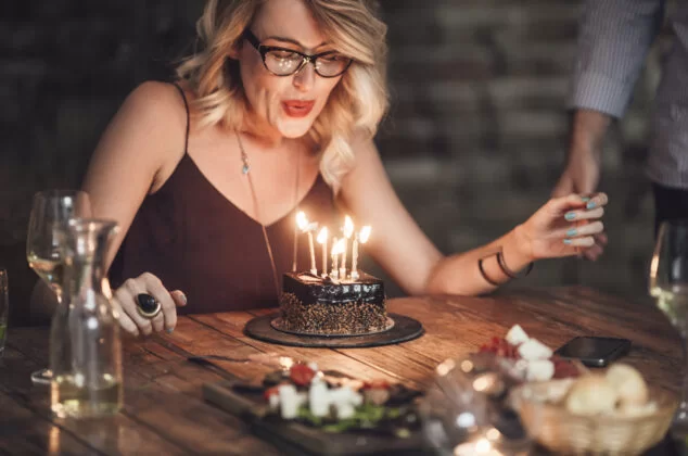 Woman blowing out the candles on her birthday cake