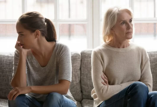 A woman and her estranged daughter sitting next to each other quarreling