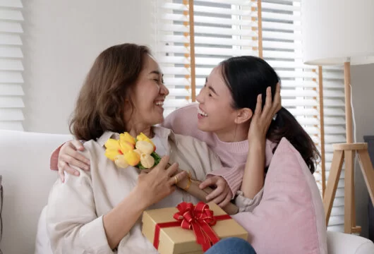 Young woman giving birthday flowers and a gift to a woman of God