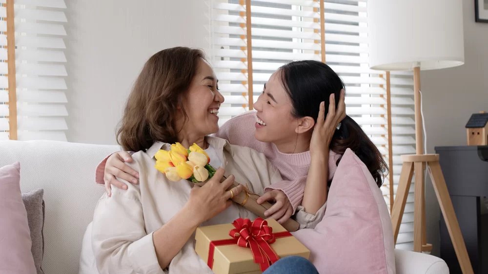 Young woman giving birthday flowers and a gift to a woman of God