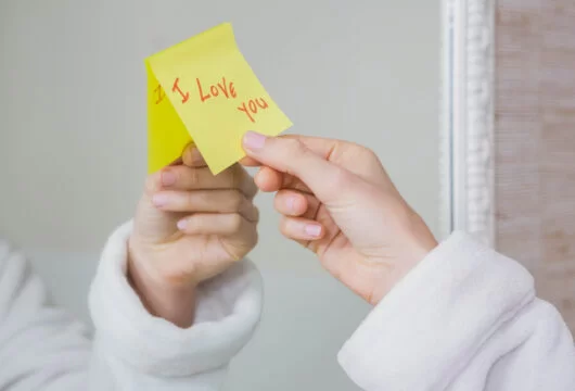 Woman's hand grabbing a short love note from her mirror
