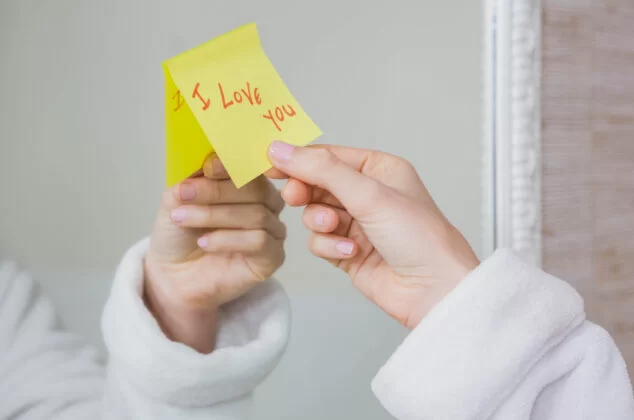 Woman's hand grabbing a short love note from her mirror