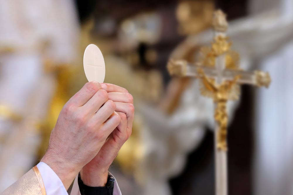 Priest's hands holding a communion wafter