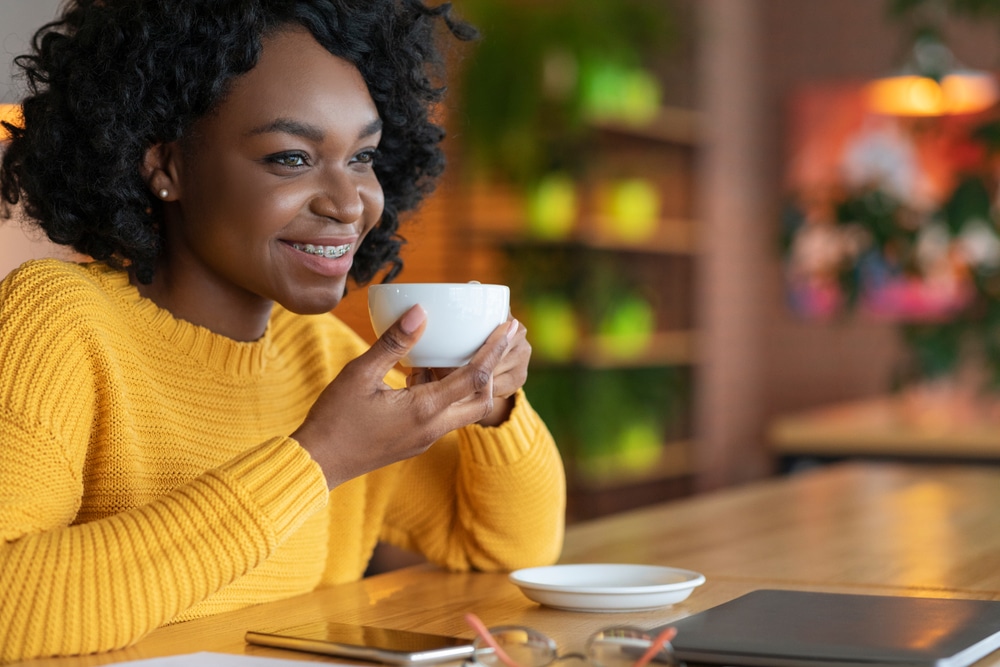 African American woman smiling while holding a cup of coffee in the morning