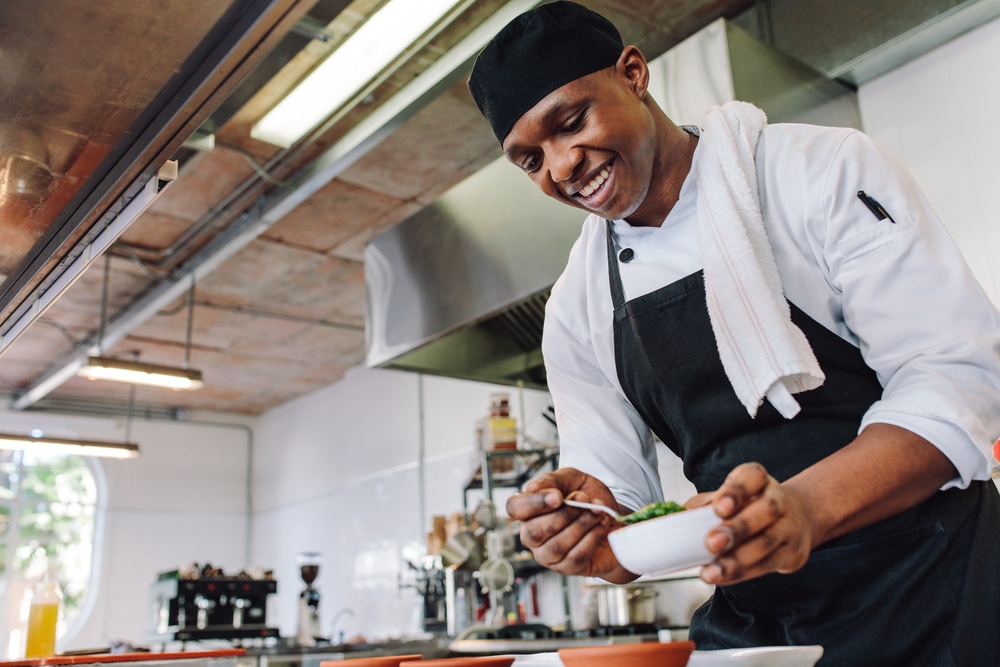 Smiling chef plating a dish in a gourmet kitchen