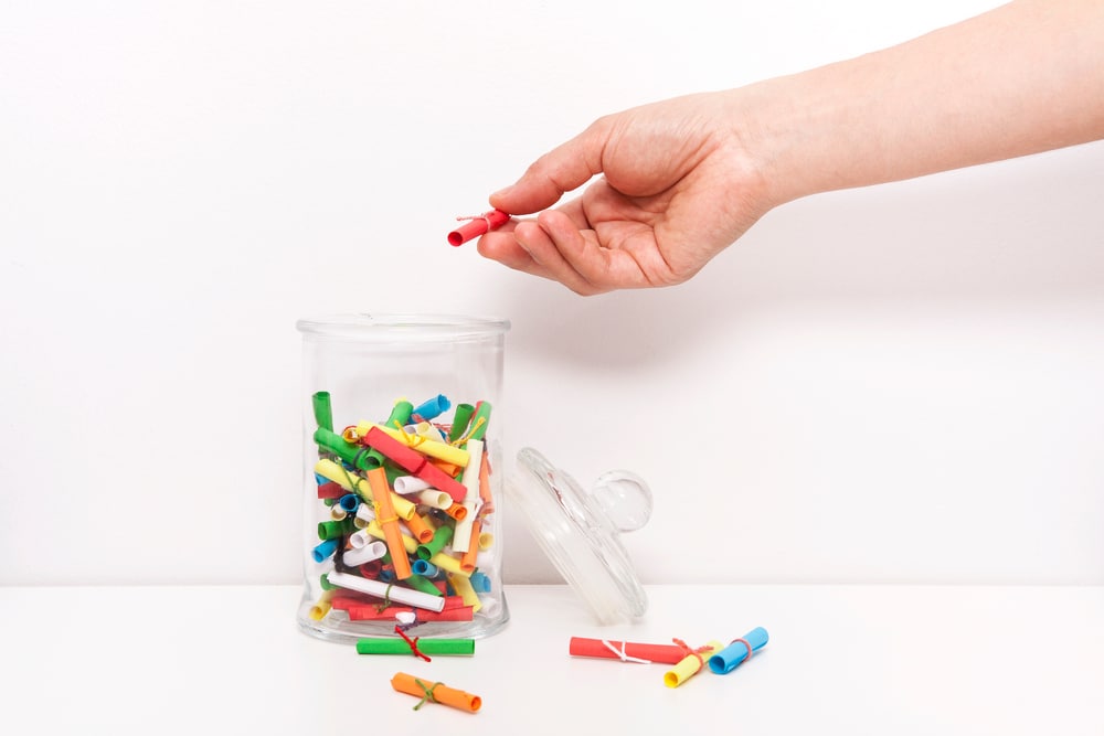 Close-up of a hand filling a jar with love capsule messages