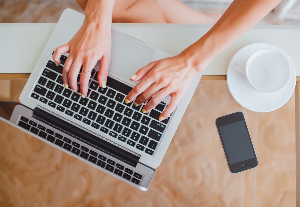 Person's hands typing an email on a laptop