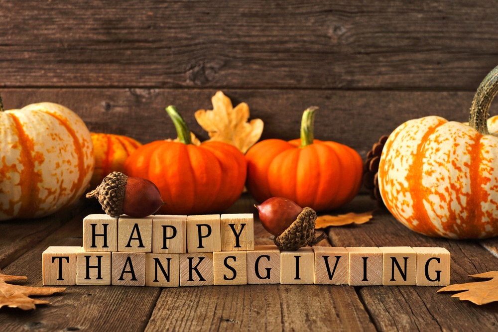 Pumpkins and acorns arranged with "Happy Thanksgiving" message blocks on a wood table