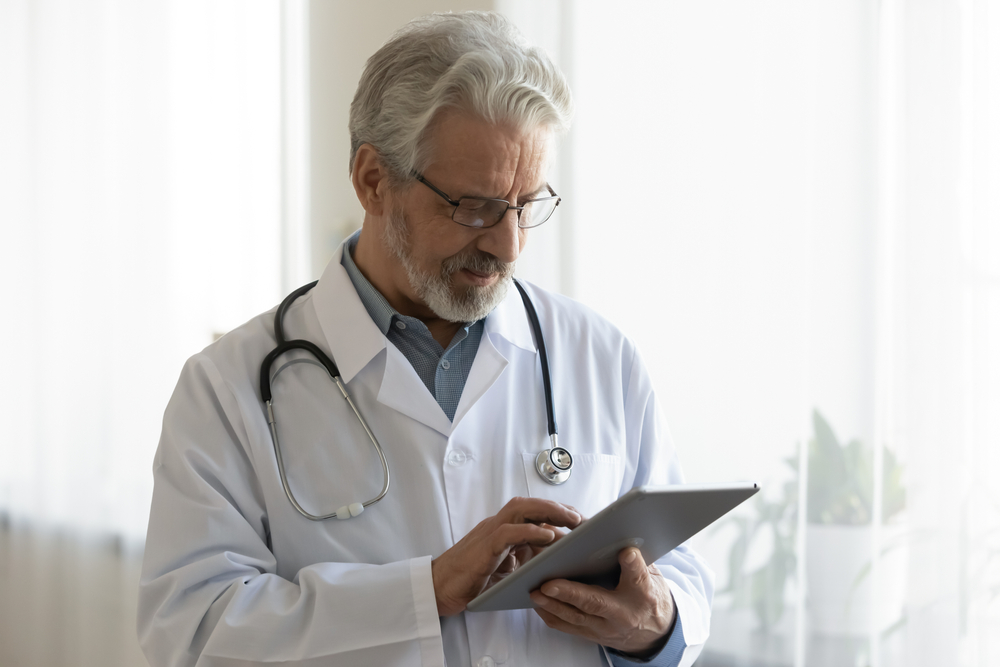 Retiring doctor checking a patient's chart on a tablet