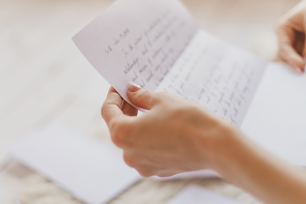 Close-up of granddaughter's hands reading a letter from her grandmother