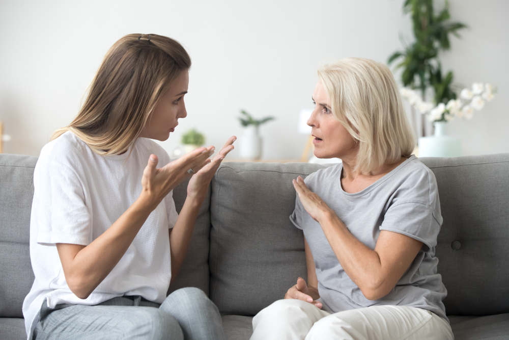 Sister-in-laws sitting on a couch arguing