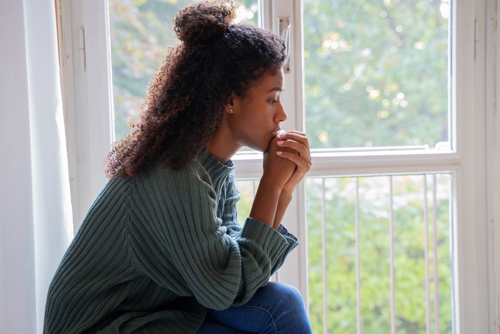 Woman sitting by the window in contemplative prayer