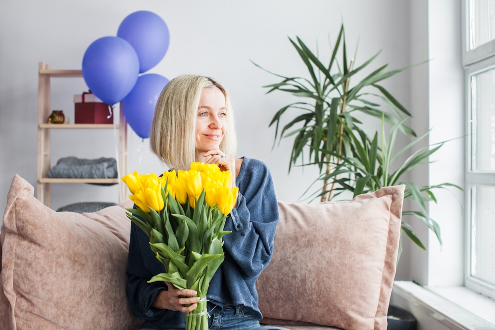 Woman holding a bouquet of yellow happy birthday flowers
