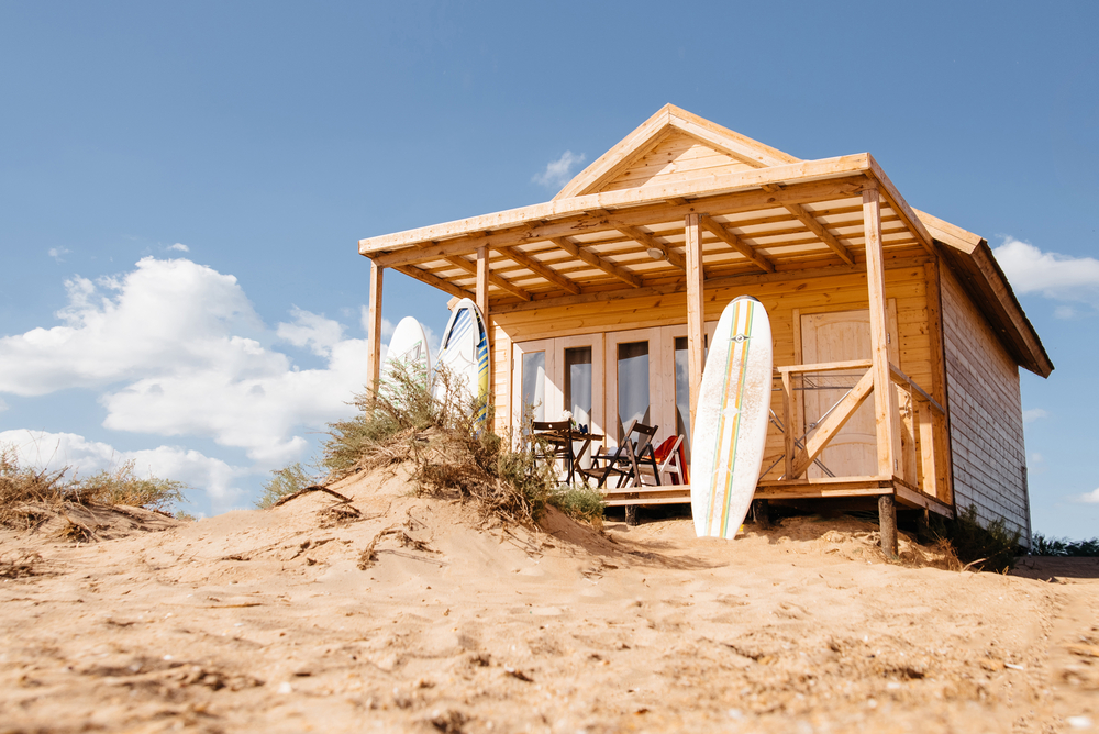 Beach house on a sand dune with a surfboard leaning against the porch