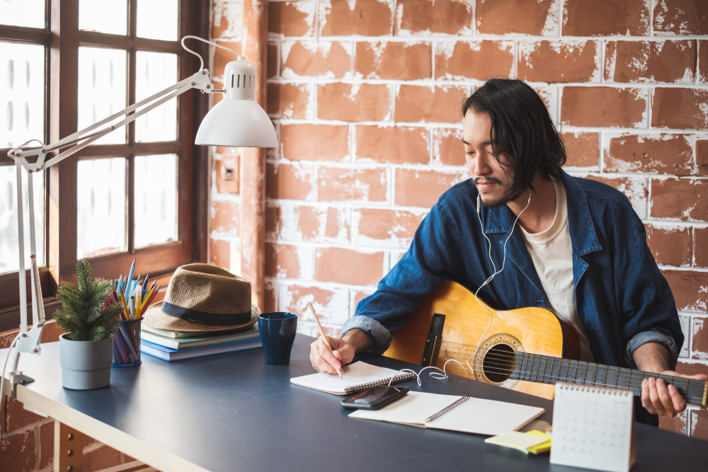 Musician playing guitar and writing a song