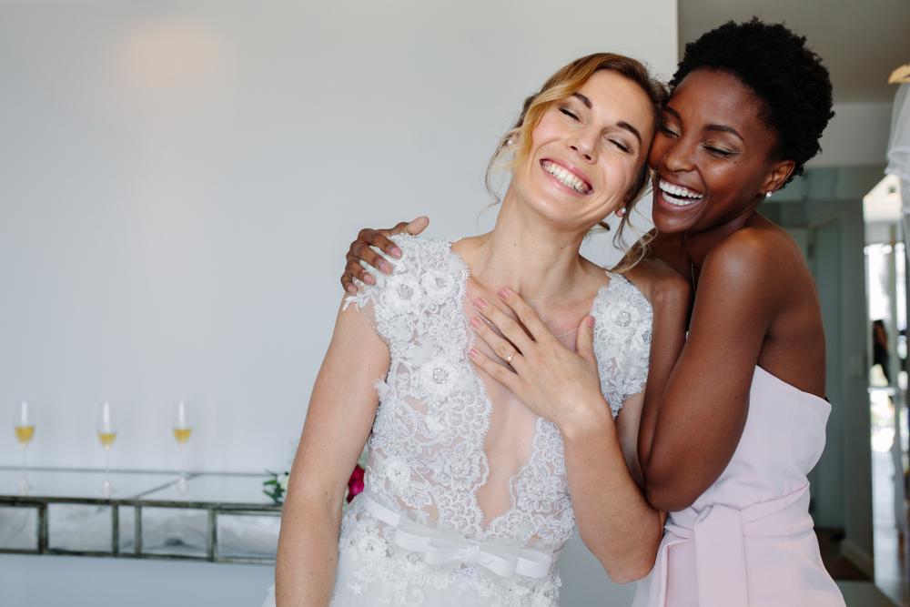 Bride and bridesmaid hugging and smiling