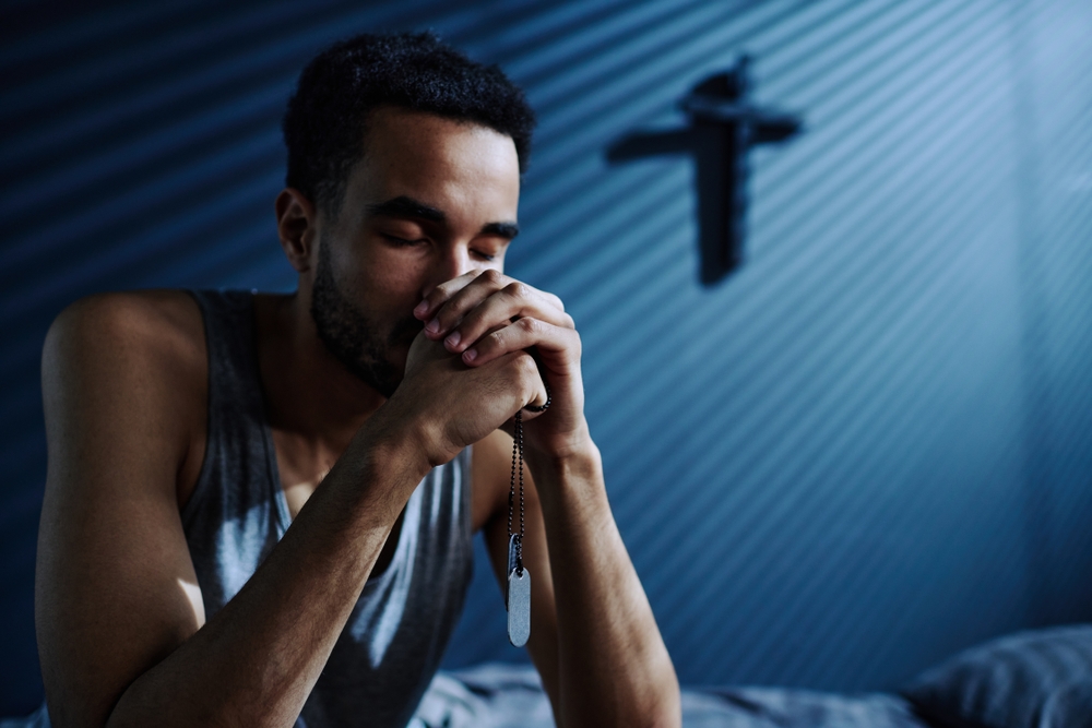 Man reciting Friday night prayers in a dark bedroom