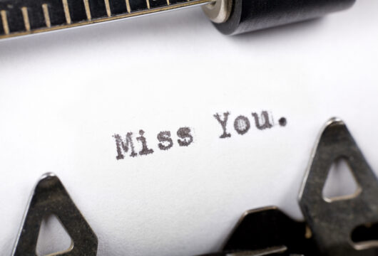 A sheet of paper with the words "Miss You." typed on it with a typewriter