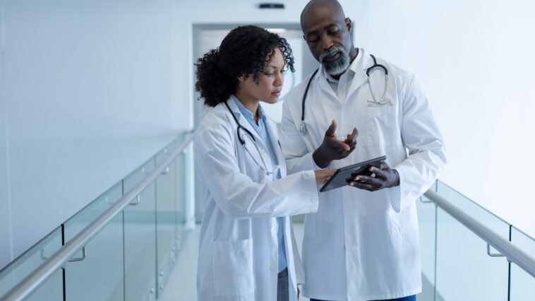 Two doctors looking at a tablet in the hallway of the hospital