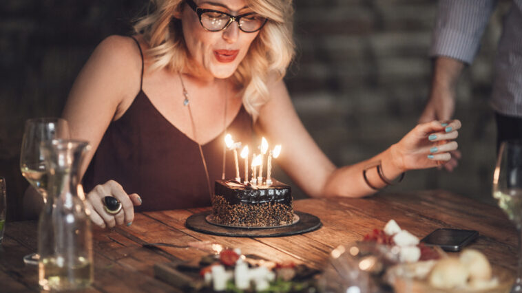 Woman blowing out the candles on her birthday cake