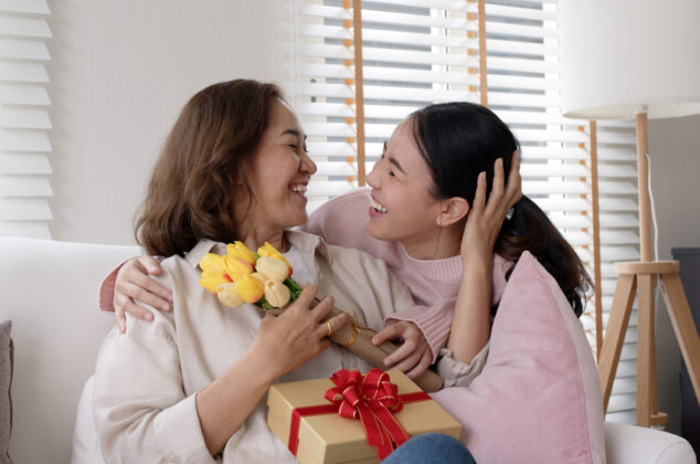 Young woman giving birthday flowers and a gift to a woman of God
