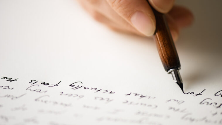 Close-up of a parent's hand writing a letter to a daughter making bad choices