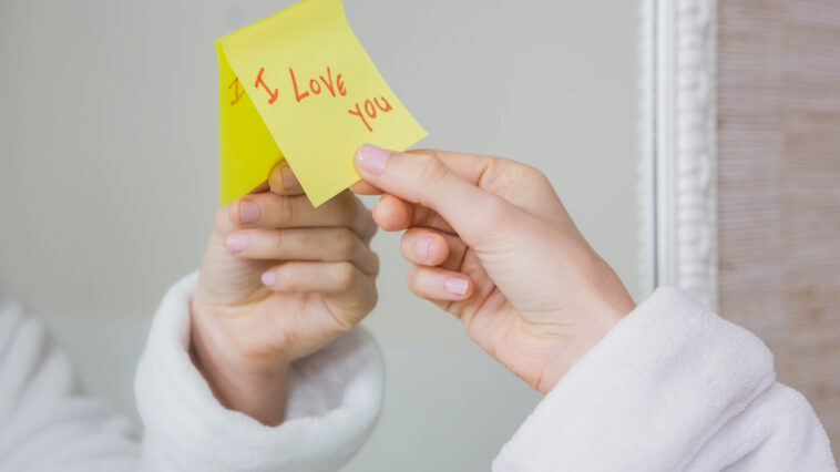 Woman's hand grabbing a short love note from her mirror